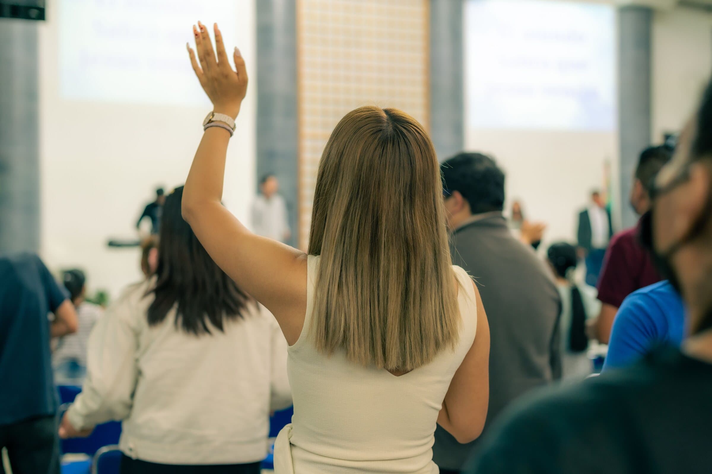A workshop room with the audience seated with their backs to the camera and the presenter at the far end, in front of a whiteboard