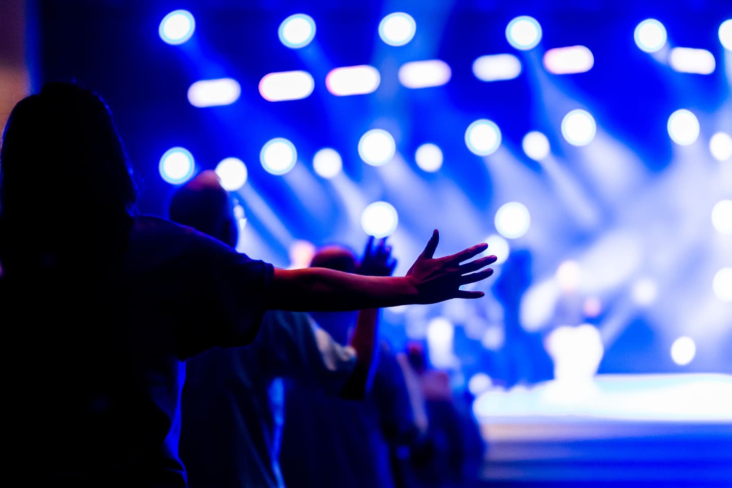 A crowd with raised arms at a blue-lit event